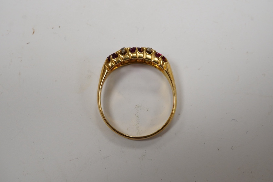 A late Victorian 18ct gold and three stone ruby set half hoop ring, with four stone diamond chip spacers, size P/Q, gross weight 3.2 grams. Condition - poor to fair